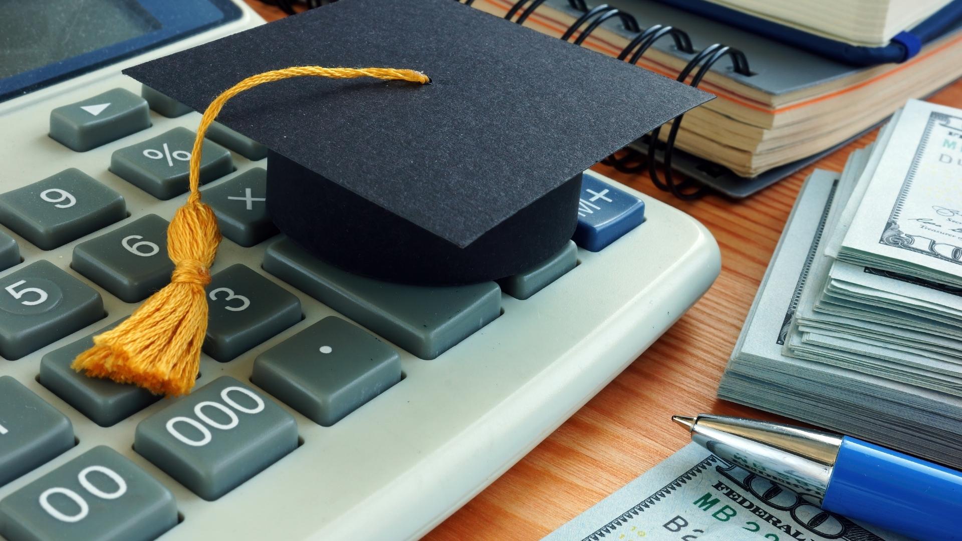 graduation cap on calculator - student loan concept